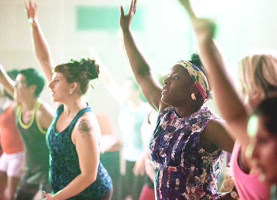 Participants at dance class with hands in air.