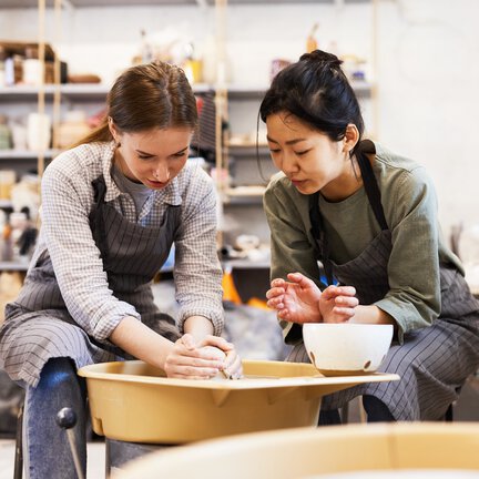 Women using potter's wheel at pottery class.